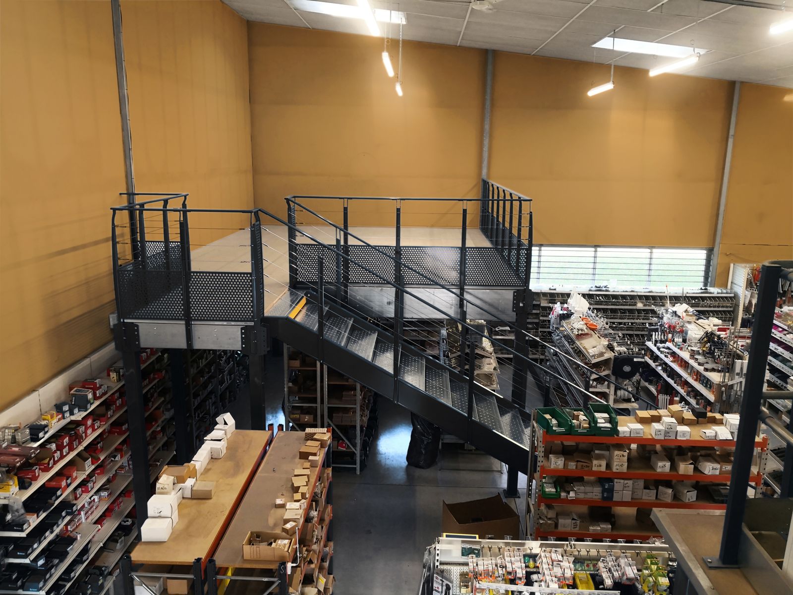 Lagerbühne im Baumarkt schafft eine zweite Verkaufsebene mit Geländer, Treppe und Regalen darunter