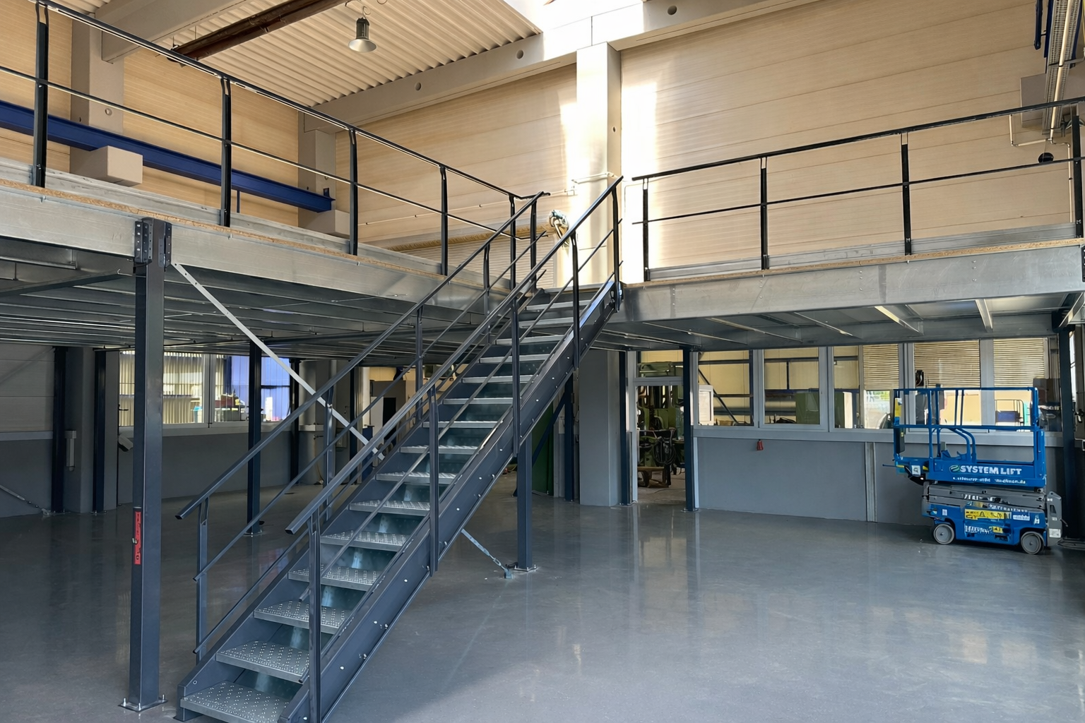 Maverlo Lagerbühne mit integrierter Treppe und Geländer gemäß Sicherheitsstandards für Industriehallen.