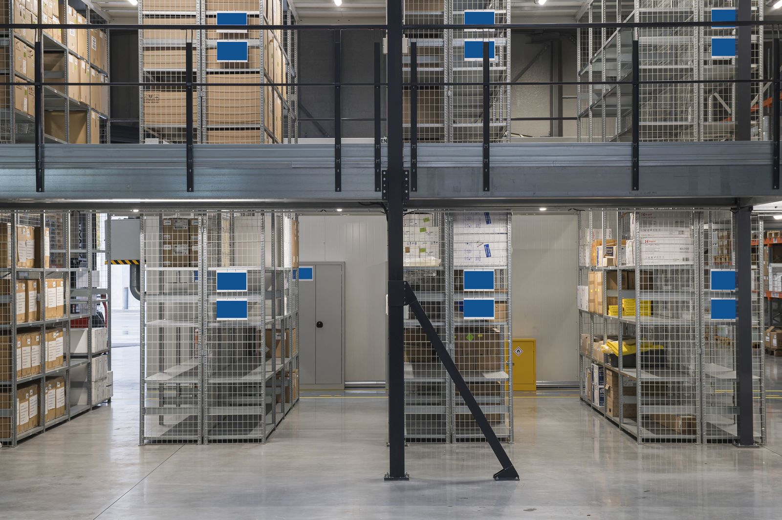 Zweigeschossige Lagerbühne mit Fachbodenregalen und Treppe in einer hellen Lagerhalle